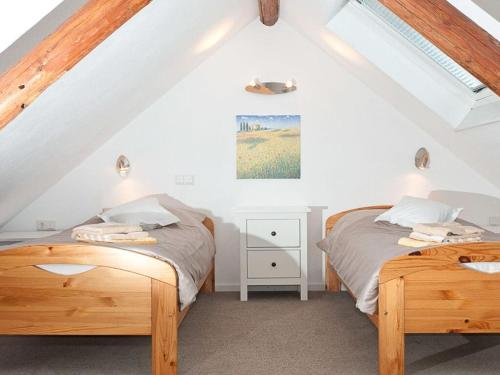 2 Betten in einem Schlafzimmer im Dachgeschoss mit weißen Wänden in der Unterkunft Casa Schalkenmehren Grande in Schalkenmehren