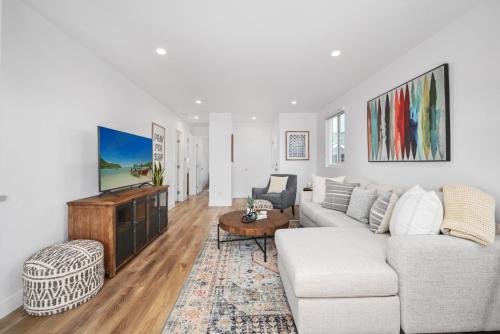 a living room with a couch and a tv at Remodeled - Modern - 2 Bedroom - Walk to the Beach in Newport Beach