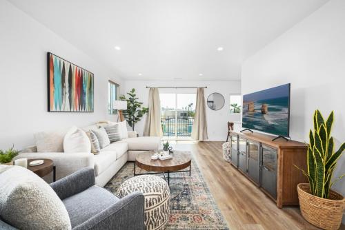 a living room with a couch and a tv at Remodeled - Modern - 2 Bedroom - Walk to the Beach in Newport Beach