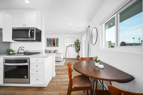 a kitchen and dining room with a table and a stove at Remodeled - Modern - 2 Bedroom - Walk to the Beach in Newport Beach