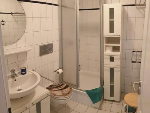 a white bathroom with a shower and a sink at Holiday apartment wind force 8 in Langeoog