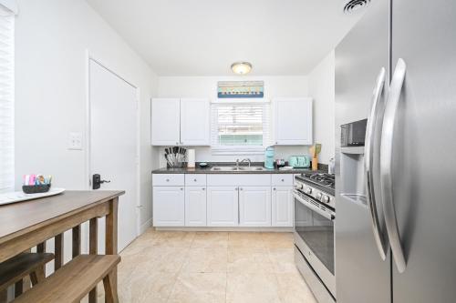 a kitchen with white cabinets and a stainless steel refrigerator at San Clemente Bungalow with jacuzzi Close to the Beach in San Clemente