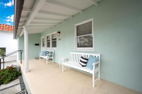 a porch with two white chairs and a window at San Clemente Bungalow with jacuzzi Close to the Beach in San Clemente