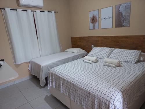 a bedroom with two beds and a window at Pousada Chalé Mar Rio 1° andar in Galinhos