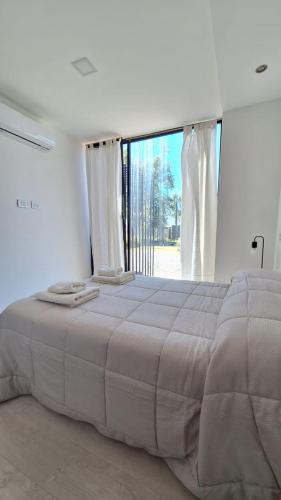 a large bed in a white room with a large window at Cubil Naranja. Casa conteiner 2 dormitorios in General Roca