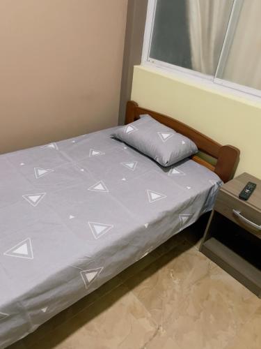 1 cama con edredón gris y ventana en salome apart, en Tarapoto