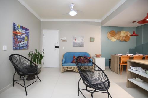 ein Wohnzimmer mit 2 Stühlen und einem Tisch in der Unterkunft Apartamento Praia do Tombo Guarujá 120m do mar in Guarujá