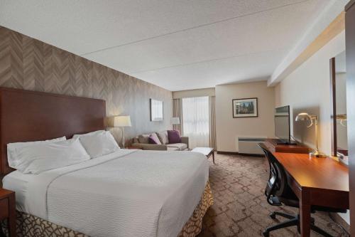 Best Western Plus Otonabee Inn في بيتربورو: غرفة الفندق بسرير كبير ومكتب