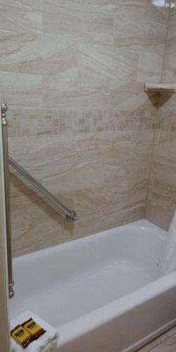 a bathroom with a bath tub with a tile wall at Best Western Plus Otonabee Inn in Peterborough