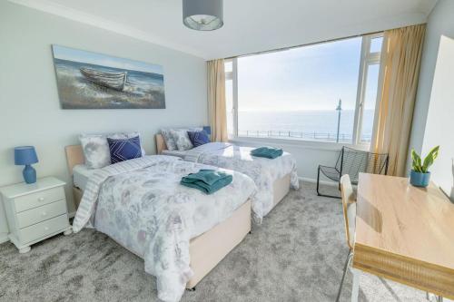 a bedroom with two beds and a large window at Stunning seaside penthouse apartment with balcony in Newlyn