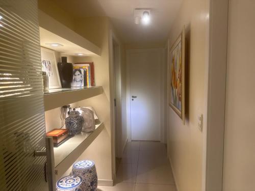 einen Flur mit einer weißen Tür und ein Zimmer mit einem Regal in der Unterkunft Apartamento Luxo Le Parc in Salvador