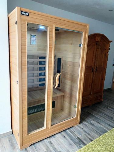 a wooden cabinet with a glass door in a room at Allgäu-Chalet Kaufbeuren in Kaufbeuren