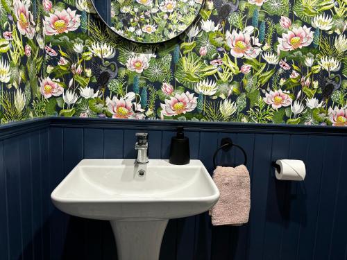 een witte wastafel in een badkamer met bloemenbehang bij The Happy Heron in Donegal