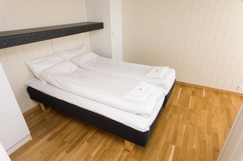 a small bed in a room with white sheets at Mones Feriesenter in Mandal