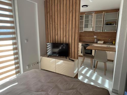 1 dormitorio con TV y cocina con mesa en Apartmani Marković, 