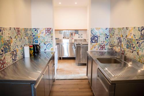 タオルミーナにあるTaormina Holiday Apartmentのカラフルなタイルのキッチン(ステンレス製のカウンタートップ付)