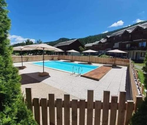 - une piscine avec des parasols à côté d'une clôture dans l'établissement Appartement 4 personnes Puy Saint Vincent 1800 pieds des pistes, à Puy-Saint-Vincent