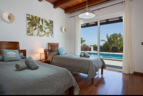 a bedroom with two beds and a view of a pool at Villa Pipa Puerto Calero in Puerto Calero