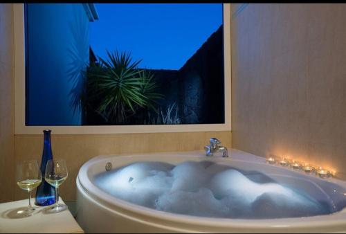 a bath tub with two wine glasses and a picture at Villa Pipa Puerto Calero in Puerto Calero