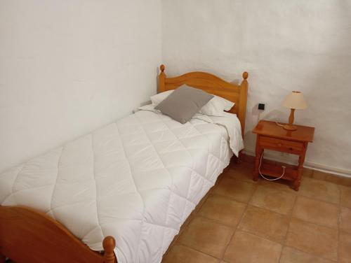 1 dormitorio con 1 cama y 1 mesa con lámpara en Casa de María del Pilar, en Taibique