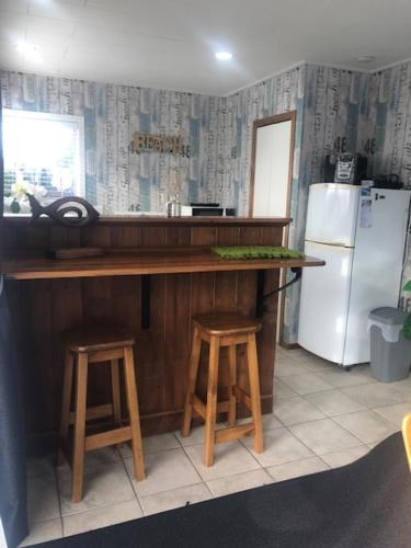 a kitchen with a counter and a refrigerator and stools at Clyde Suite in Tauranga