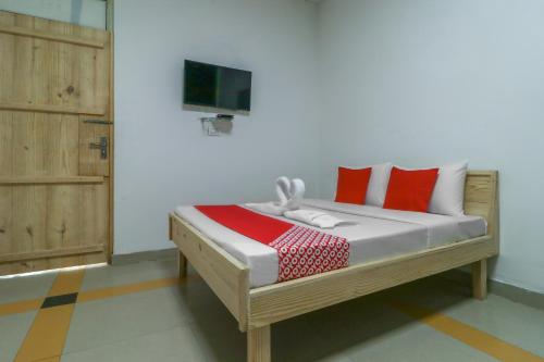 a bedroom with a bed with red pillows and a tv at OYO Flagship Mg Mehak Garden in Darbi
