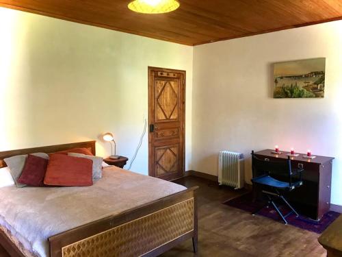 a bedroom with a bed with a desk and a door at Maison des Séquoias - Parc 1 hectare- in Veyrac