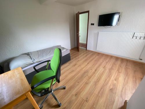 a room with a green chair and a bed and a desk at Einfache Schlafmöglichkeit mit Gemeinschaftsküche und Bad in Brombachtal