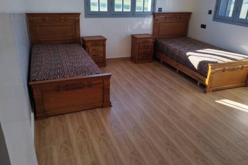 two beds in a room with wooden floors at Maison+piscine dans une ferme benslimane in O Ben Slimane