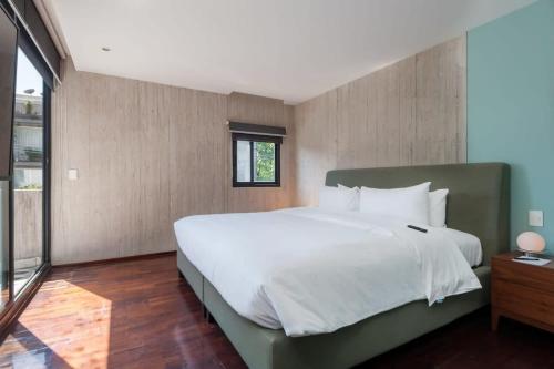 Un dormitorio con una gran cama blanca y una ventana en Spectacular 2BR Duplex in Roma Norte, en Ciudad de México