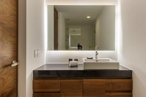 baño con lavabo y espejo grande en Spectacular 2BR Duplex in Roma Norte, en Ciudad de México