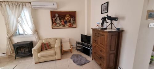 a living room with a chair and a television at Fab Sea and Mountain View Villa, walking distance from the Sandy Beach in Yialia