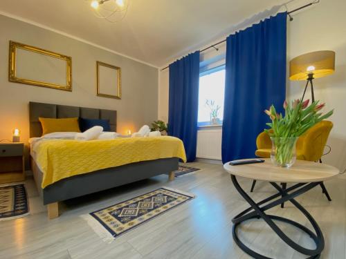 a bedroom with a bed with blue curtains and a table at Apartamenty Pod Zamkiem in Podzamcze