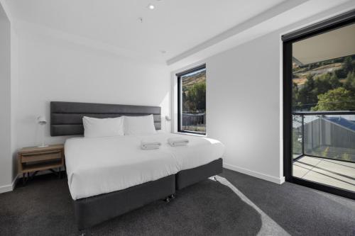 a bedroom with a white bed and a large window at Residence du Parc - Luxury Apartment in Paraparaumu Beach