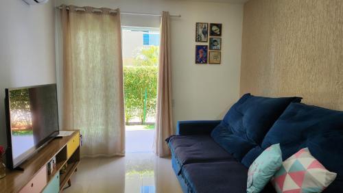 uma sala de estar com um sofá azul e uma televisão em Golden Lake RJ - Lindo como um Resort! em Arraial do Cabo