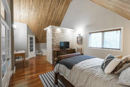 um quarto com uma cama grande e uma parede de pedra em Le Fitchbay em Magog-Orford