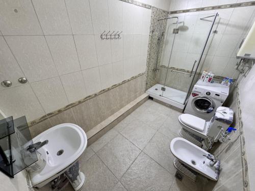 een badkamer met een wastafel en een wasmachine bij Poytakht 80 Apartments in Doesjanbe