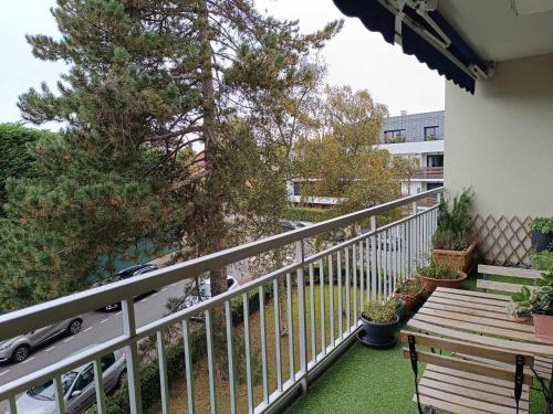 einen Balkon mit einer Holzbank und einem Baum in der Unterkunft Appartement familial in Vélizy-Villacoublay