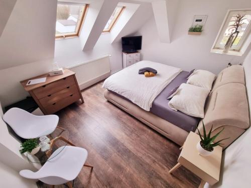 niewielka sypialnia z łóżkiem i 2 białymi krzesłami w obiekcie Penzion ORION w mieście Petrovice