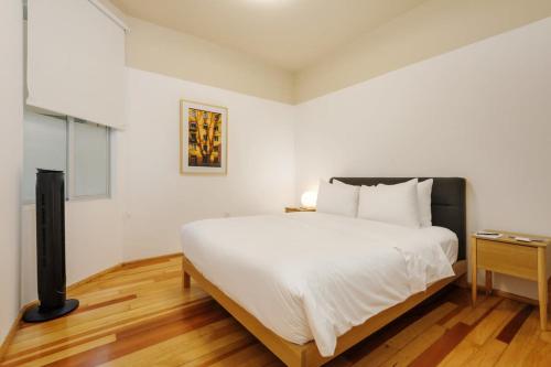 een slaapkamer met een groot wit bed en een houten vloer bij Lovely 3BR in Roma Norte in Mexico-Stad
