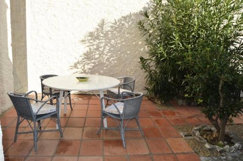 une table blanche et des chaises sur une terrasse dans l'établissement Résidence La GrifoulliÈre - VILLA 5 PIECES 7 couchages PORT LEUCATE MAE-5974, à Port-Leucate