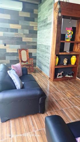 ein Wohnzimmer mit einem schwarzen Sofa und Holzboden in der Unterkunft La casa de Mamá in Coatzacoalcos