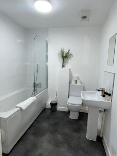 a bathroom with a tub and a sink and a toilet at 1 Bed Apartment close to Heathrow Airport in Colnbrook