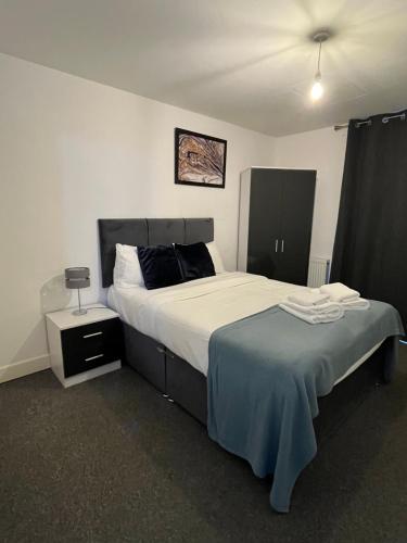 a bedroom with a large bed and a night stand at 1 Bed Apartment close to Heathrow Airport in Colnbrook