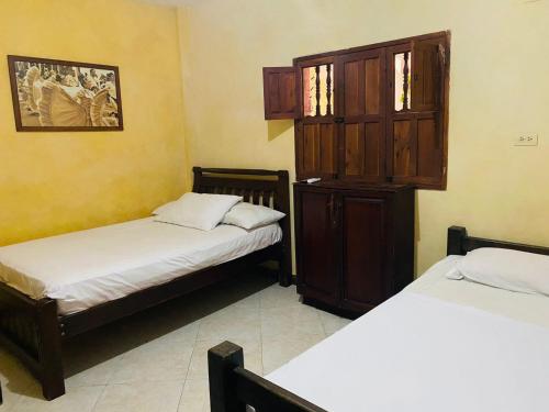 a room with two beds and a wooden cabinet at CASA MORALES in Santa Fe de Antioquia