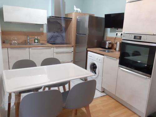 une petite cuisine avec une table et des chaises blanches dans l'établissement Appartement Centre Ville MONT DORE Vacances et Week-End Classé 3 Etoiles, à Le Mont-Dore