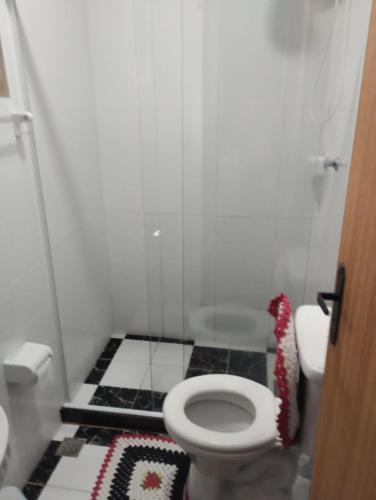 a bathroom with a toilet and black and white tiles at Residência Itaúna in Saquarema
