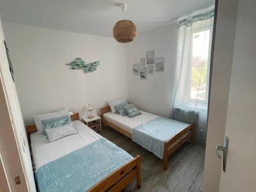 une chambre avec deux lits et une fenêtre dans l'établissement Le Grand Large - Appartement Centre Concarneau, à Concarneau