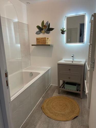 une salle de bain avec une baignoire, un lavabo et un miroir dans l'établissement Le Grand Large - Appartement Centre Concarneau, à Concarneau