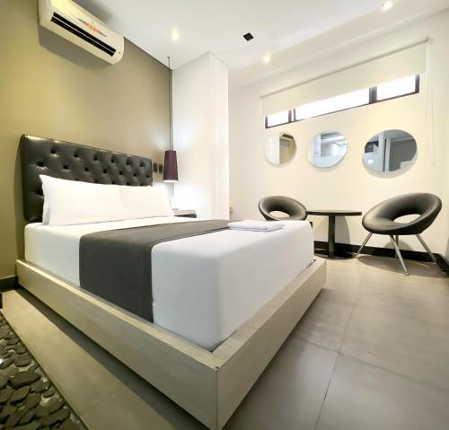 a bedroom with a bed and two chairs at Hotel 47 Medellin Center in Medellín